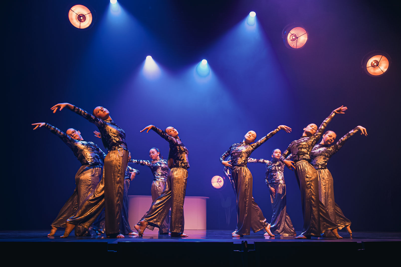 Danseurs de Fusion’Art Center en costumes dorés sous les lumières de scène.