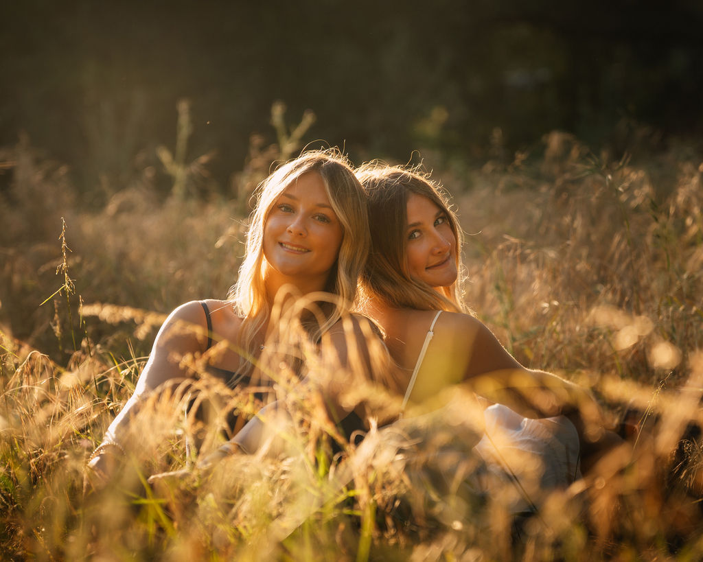 Two girls in golden grass, warm backlight