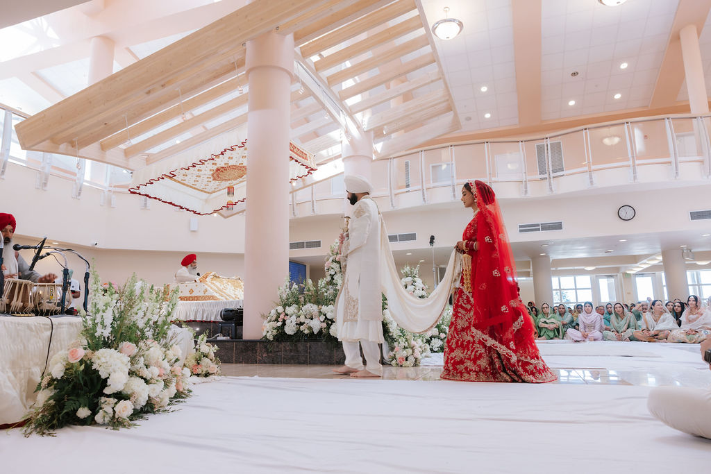Full-length Anand Karaj ceremony with Mandeep and Naveet, wedding flowers, skylit ceiling, columns, balcony and seated congregation