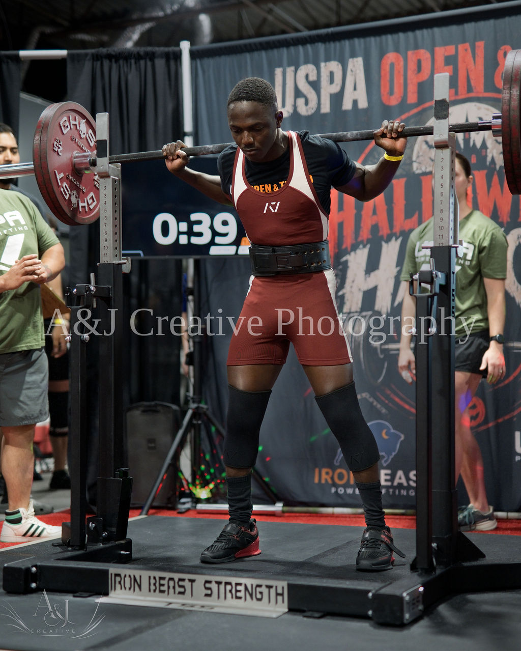 Athlete squatting with spotters at Halloween Havoc