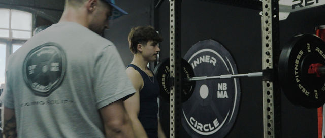 Coach spotting athlete — Inner Circle NB MA weight plate visible