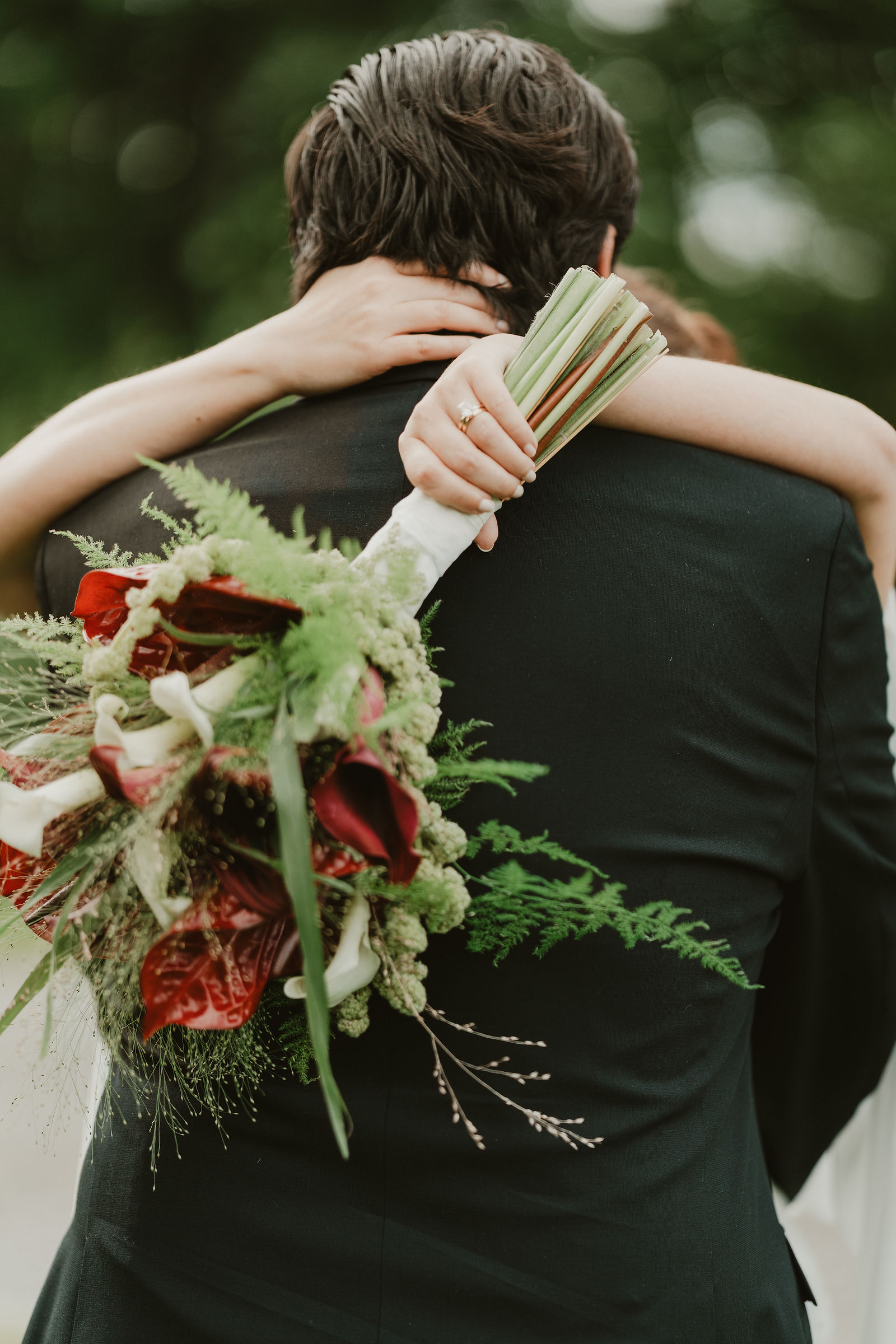 A bride embraces the groom with her bouquet over his shoulder