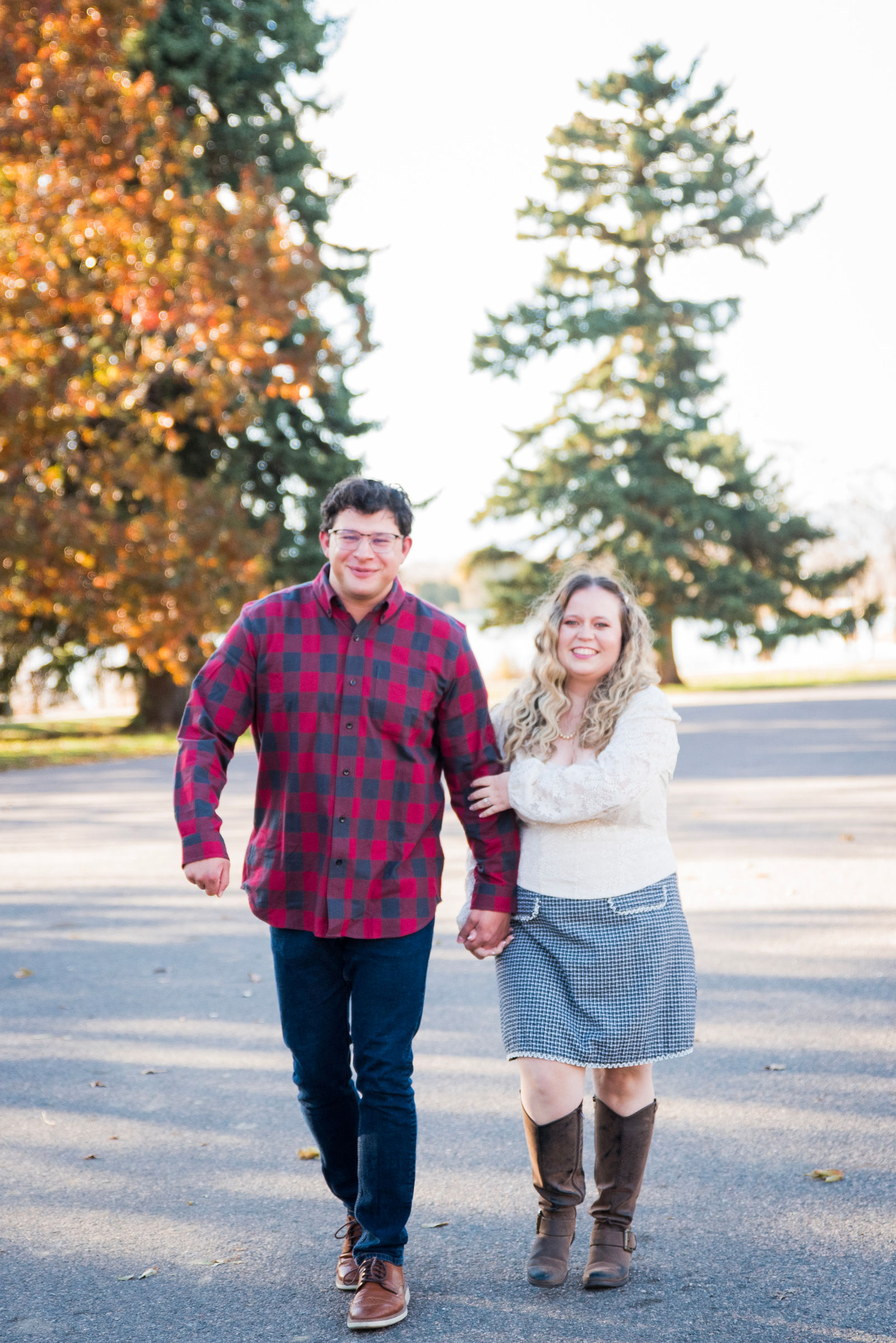 Couple in red buffalo plaid and a cream lace sweater with a grey plaid skirt among November leaves in Colorado