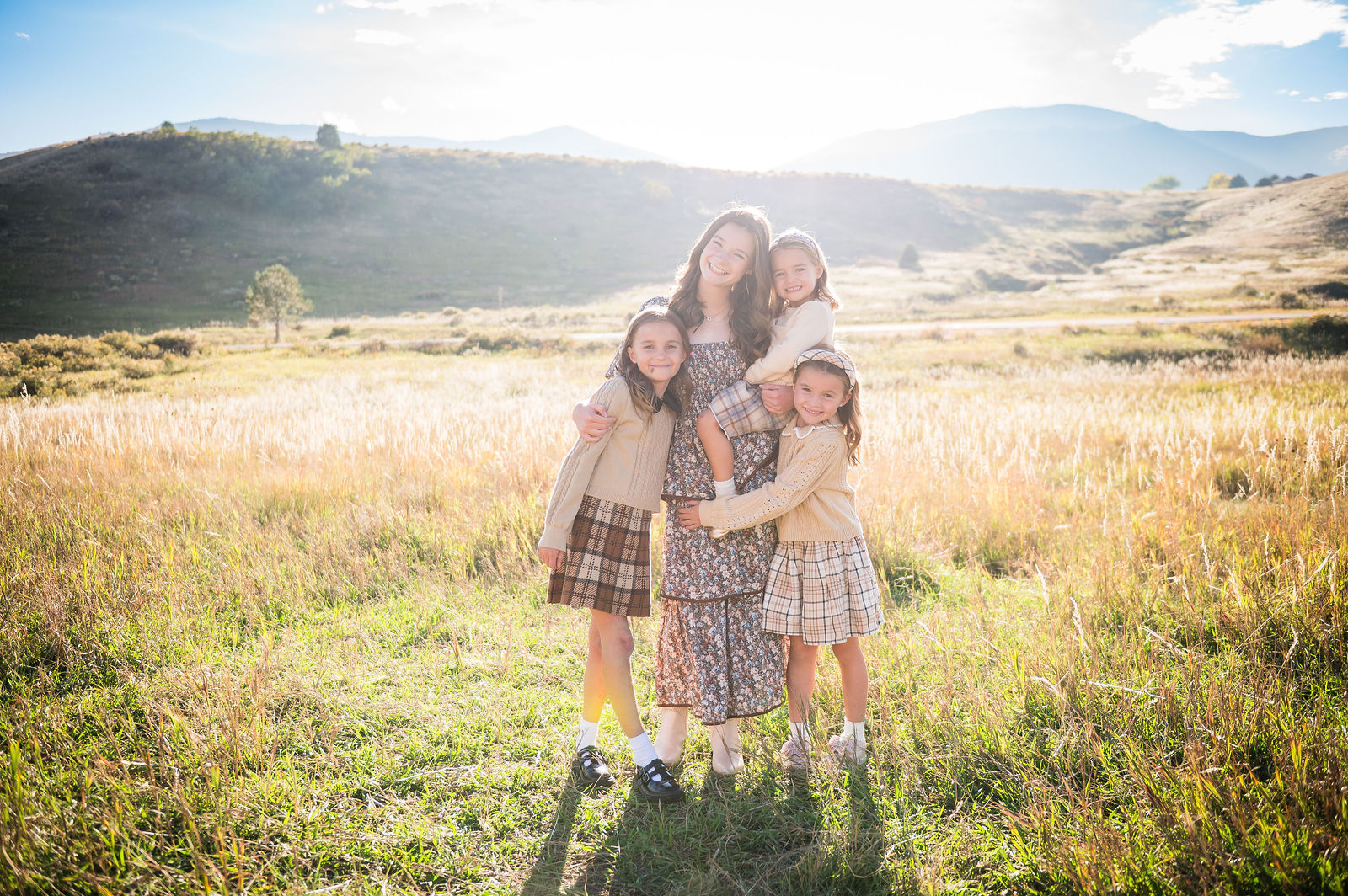 Backlit Colorado family portrait at golden hour in coordinated warm neutral fall outfits