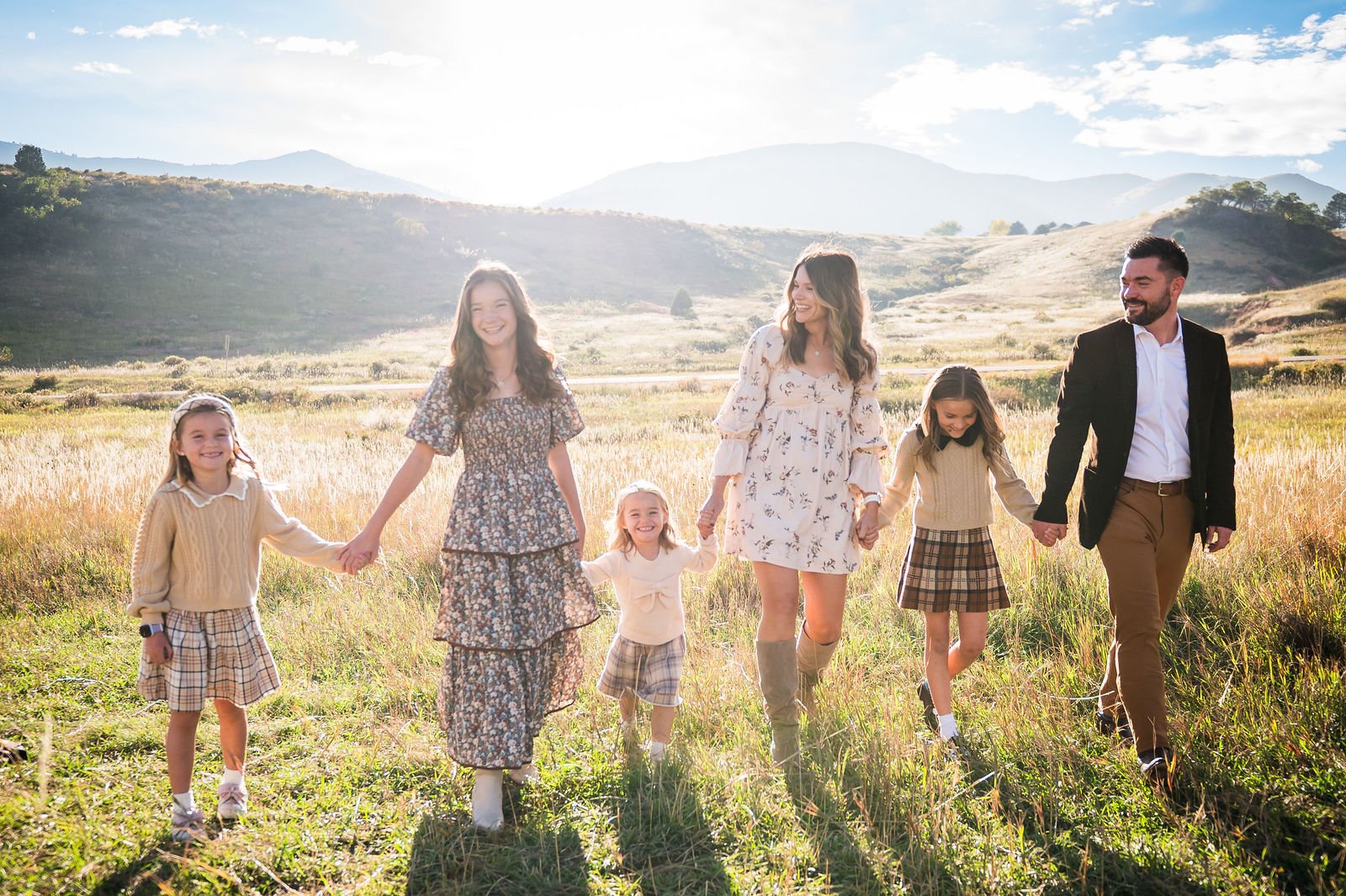 Colorado family walking through golden autumn grass at sunset in coordinated fall outfits
