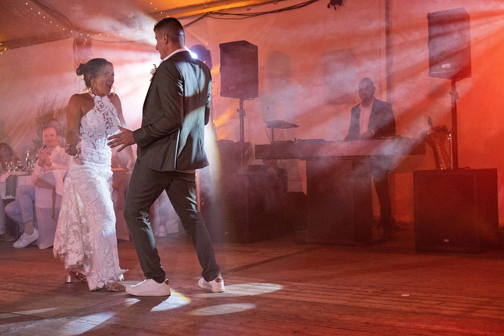 Les mariés dansent sous les lumières de la soirée DJ sous le chapiteau.