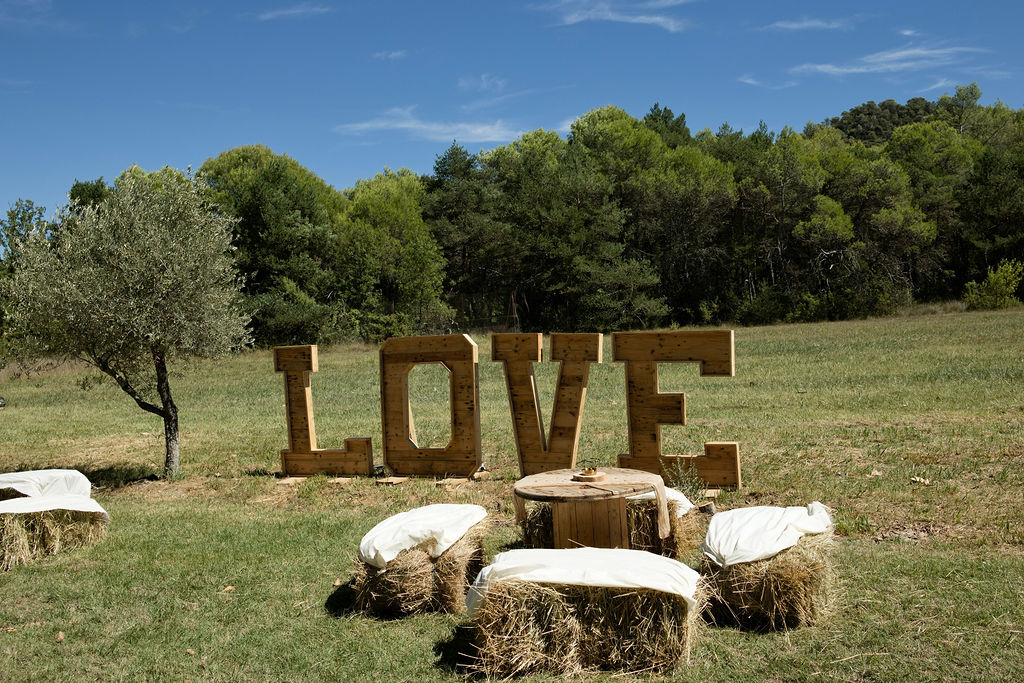 Grandes lettres LOVE en bois et assises champêtres pour la cérémonie laïque.