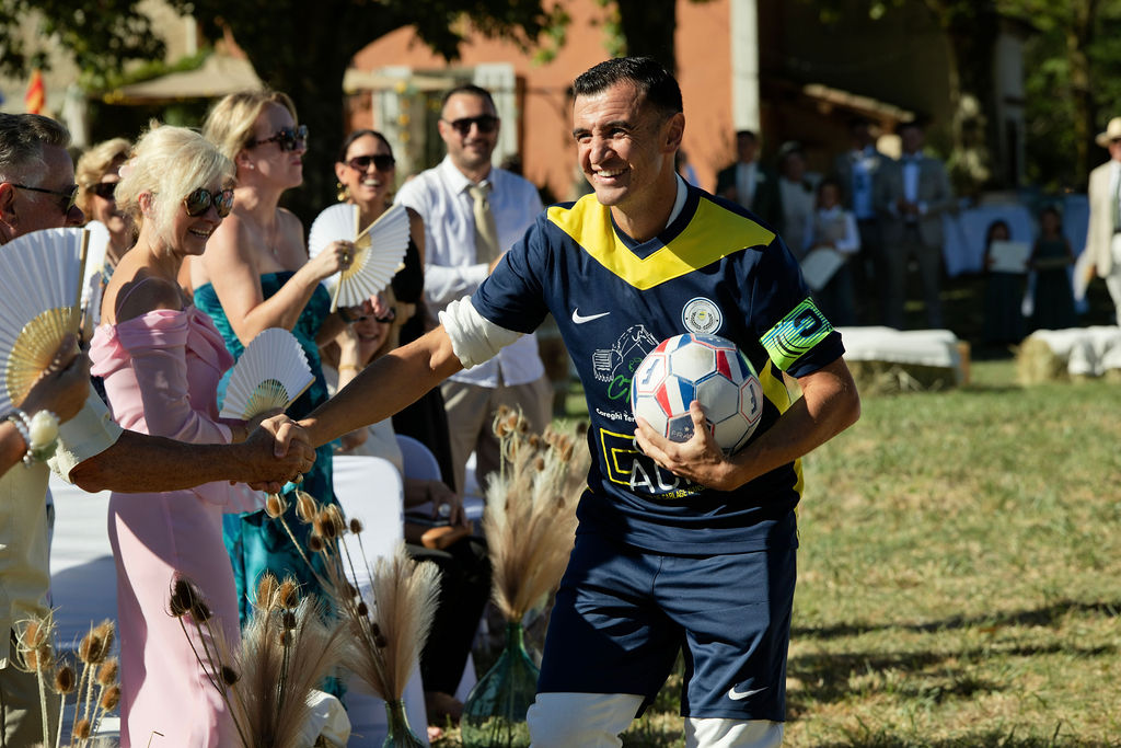 Une entrée de cérémonie avec un ballon de football et des poignées de main parmi les invités.