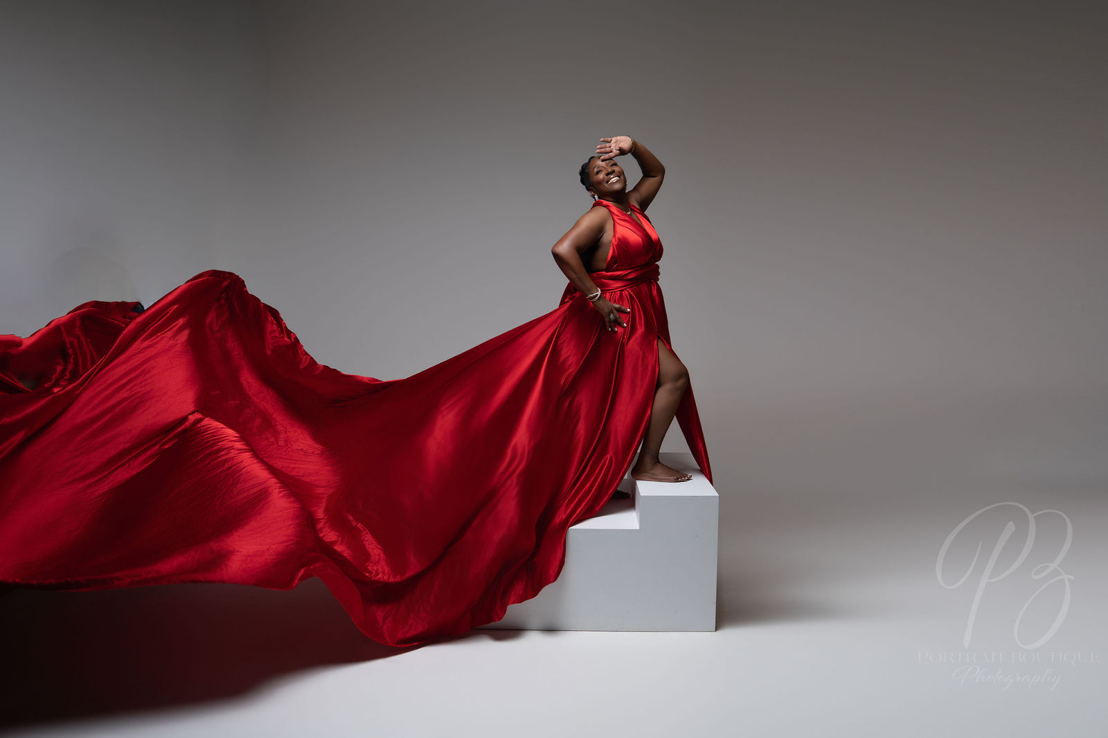 Woman in a flowing red flying dress posing on white steps