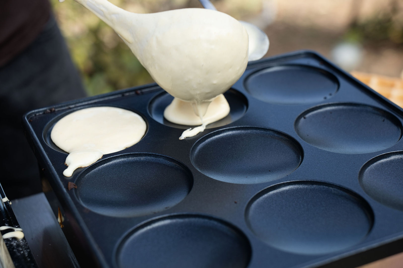 La pâte est versée dans les empreintes de la plaque à pancakes