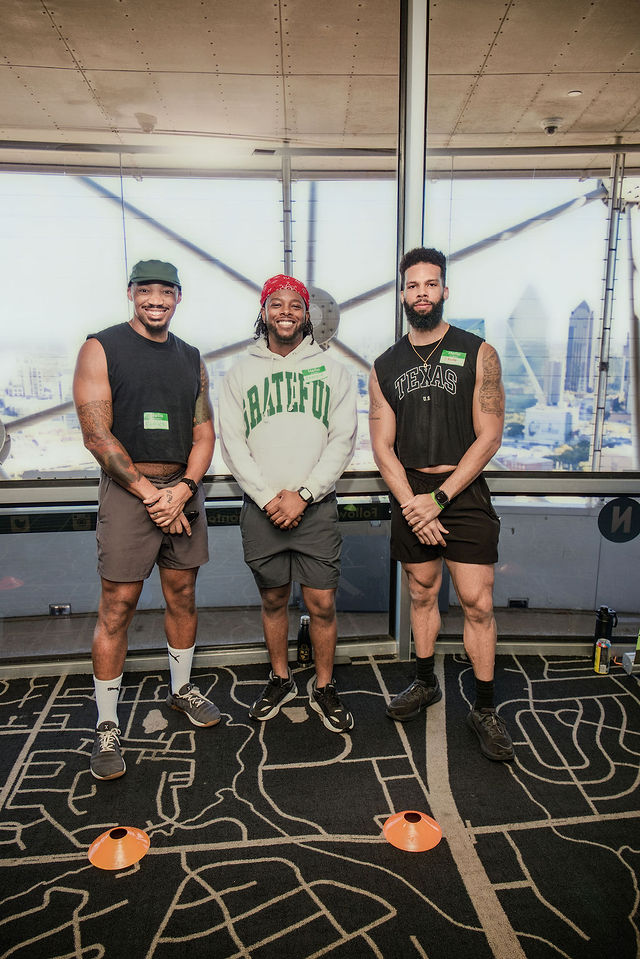 Three athletes smiling together overlooking Dallas