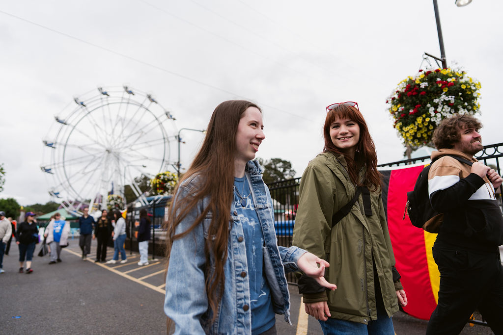 Walkers smiling at Oaks Amusement Park with the Ferris wheel behind them