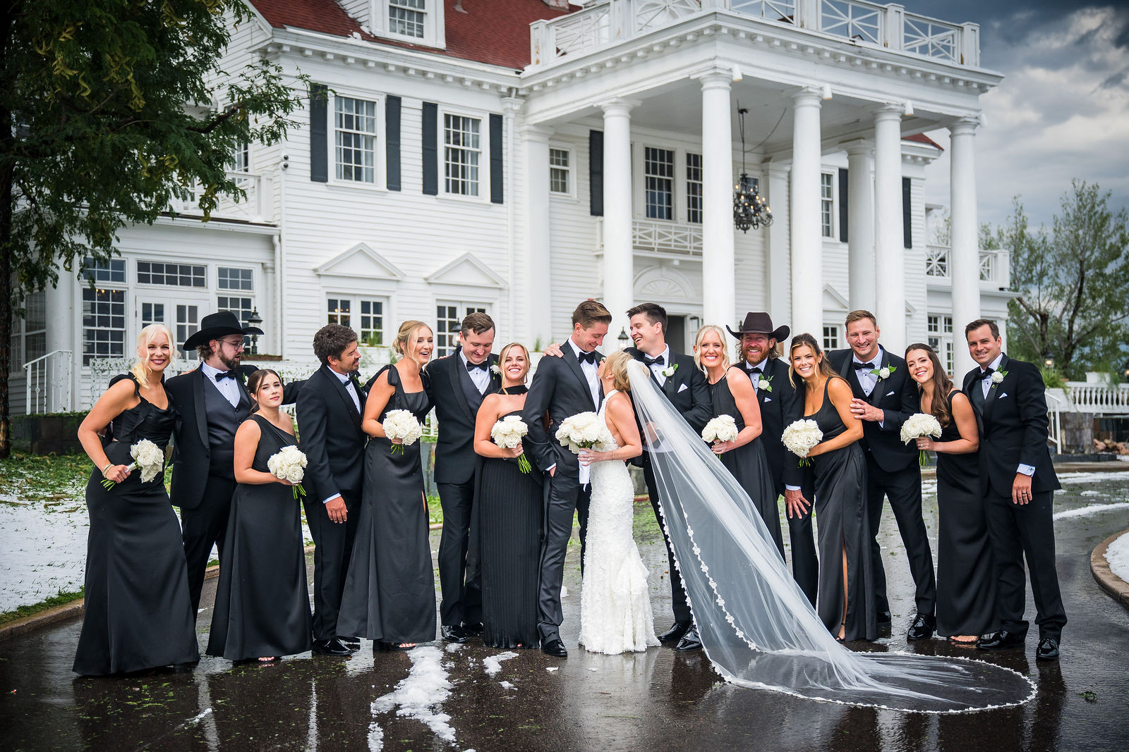 Wedding party holding the bride's veil in front of The Manor House