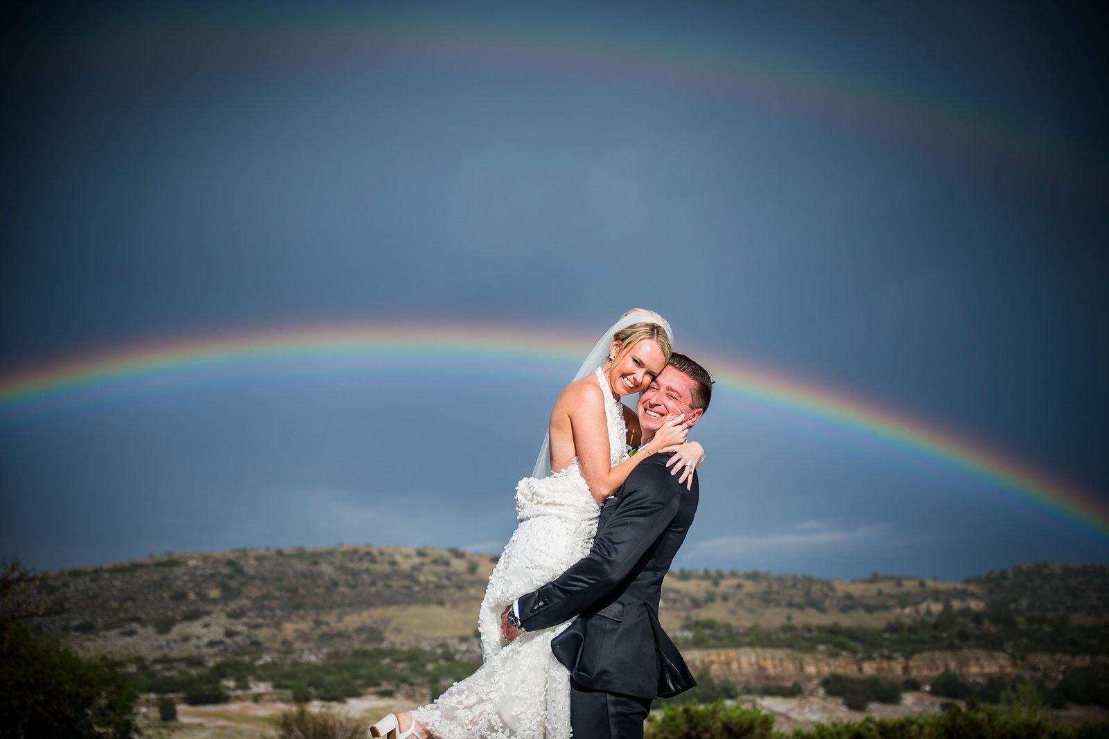 Bride and groom under a rainbow at The Manor House in Littleton, Colorado