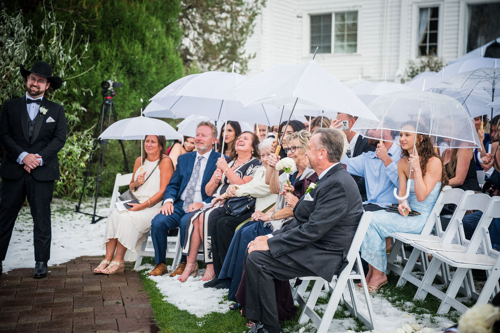 Wedding guests holding umbrellas during a rainy ceremony at The Manor House in Littleton, Colorado