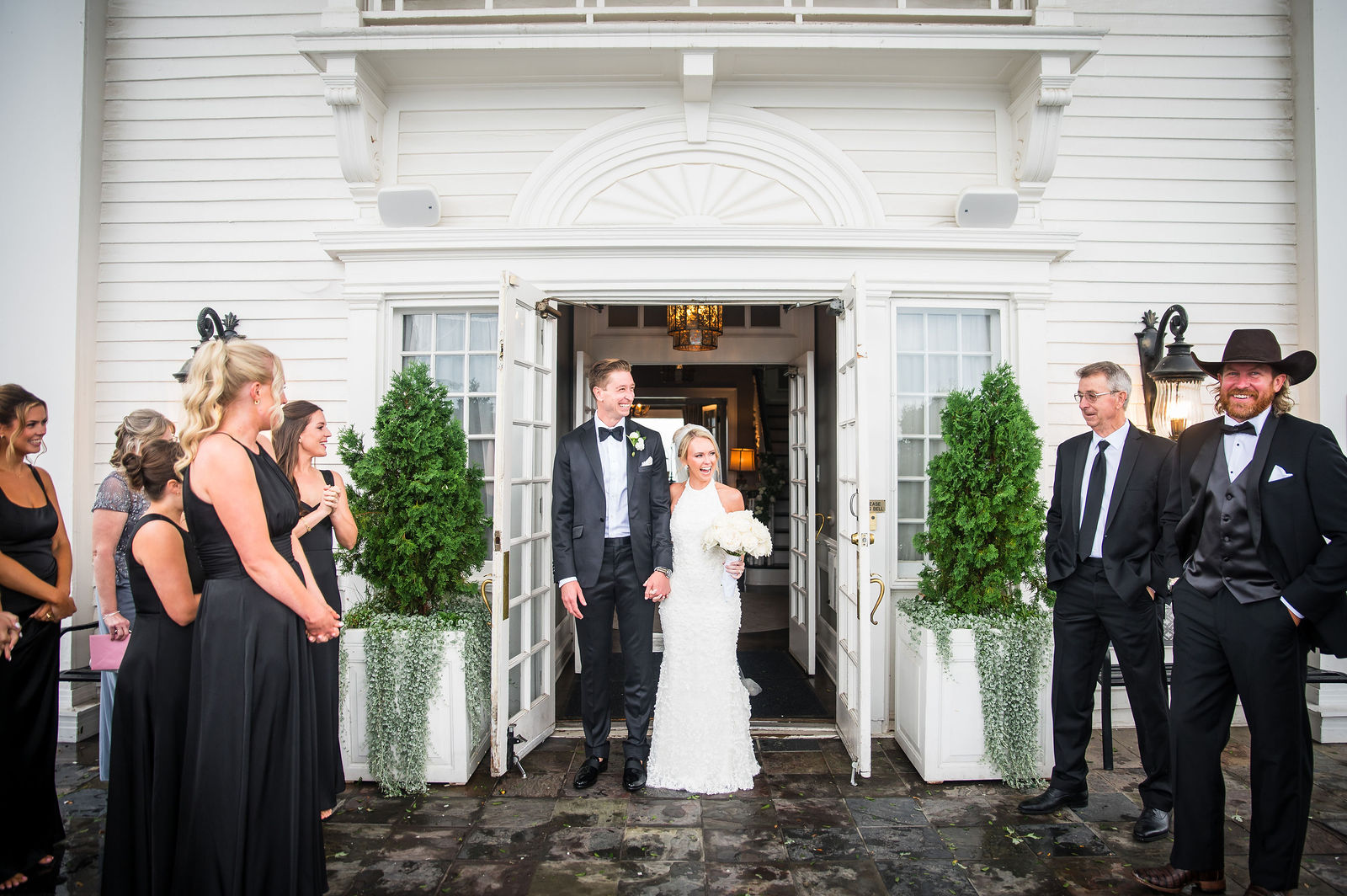 Full wedding party at the entrance of The Manor House in Littleton, Colorado