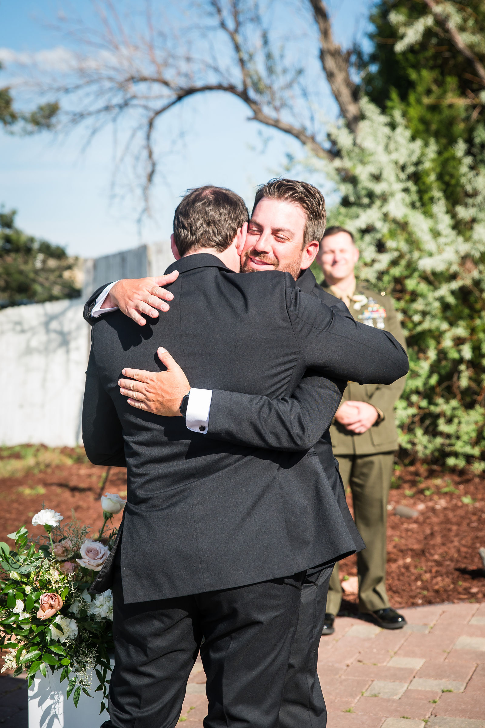 Groom embracing a guest after the ceremony at The Manor House in Littleton, Colorado