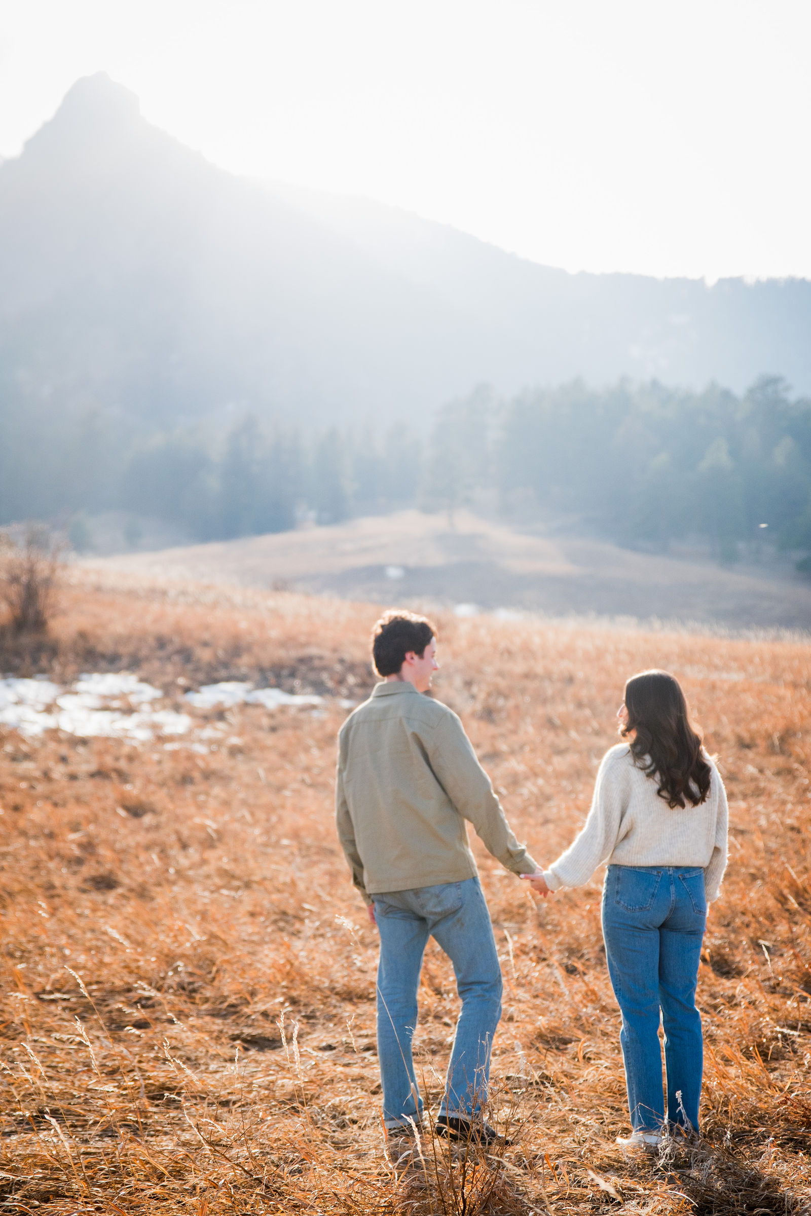 Engaged couple walking toward the Flatirons on a clear Colorado afternoon