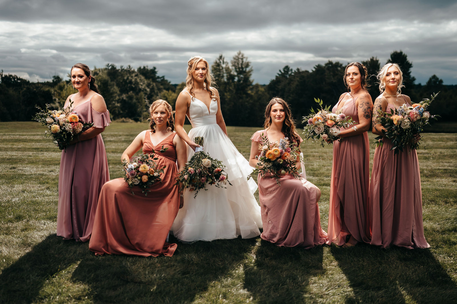 Bride with her bridesmaids on the lawn under a dramatic sky at Dell-Lea