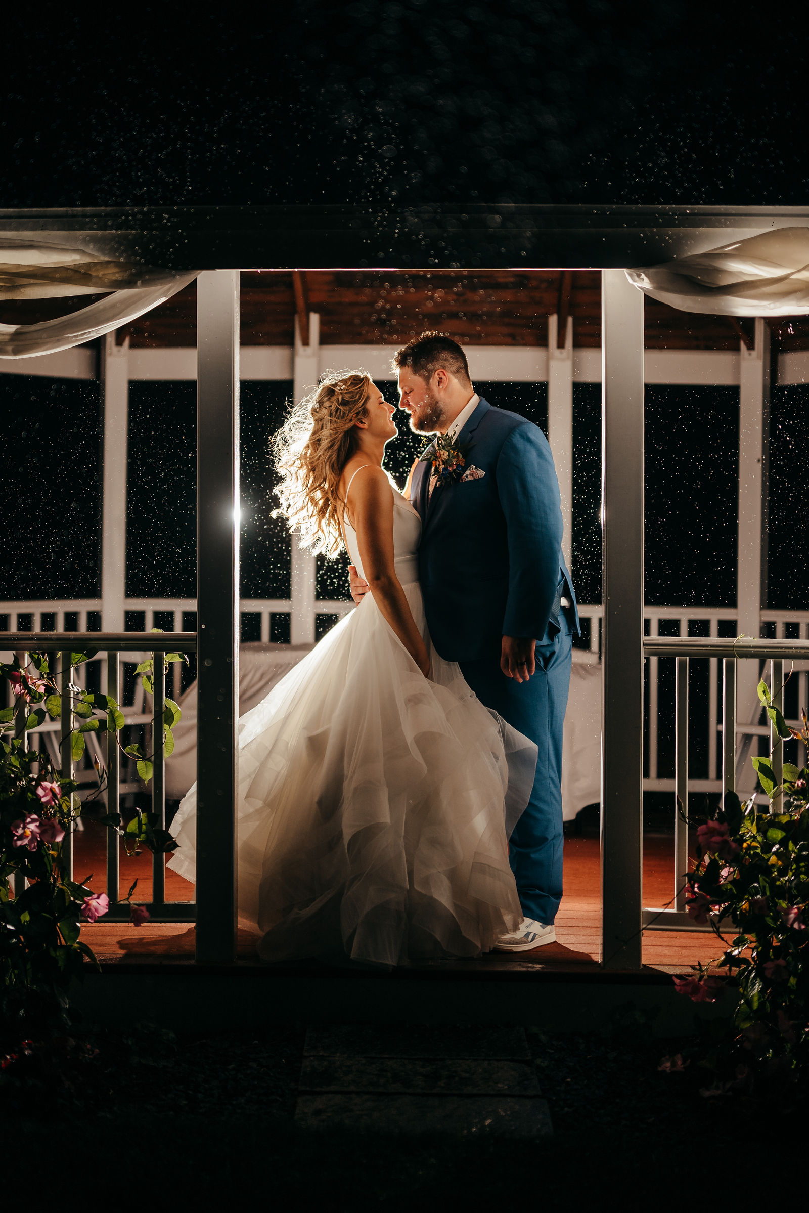 Couple kissing under the covered porch at night in warm light at Dell-Lea