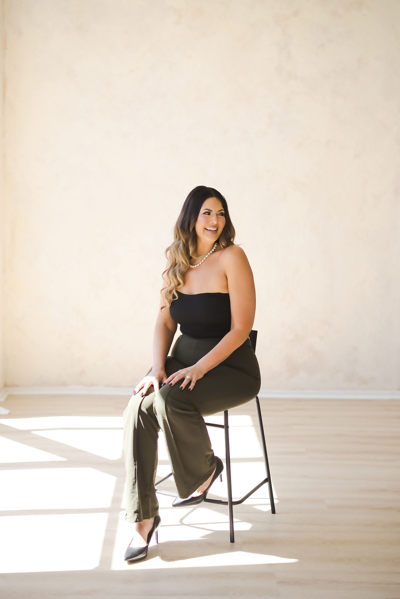 Personal brand photography of a beauty founder seated on a curved white sofa at The Studio on Fourth, Santa Rosa