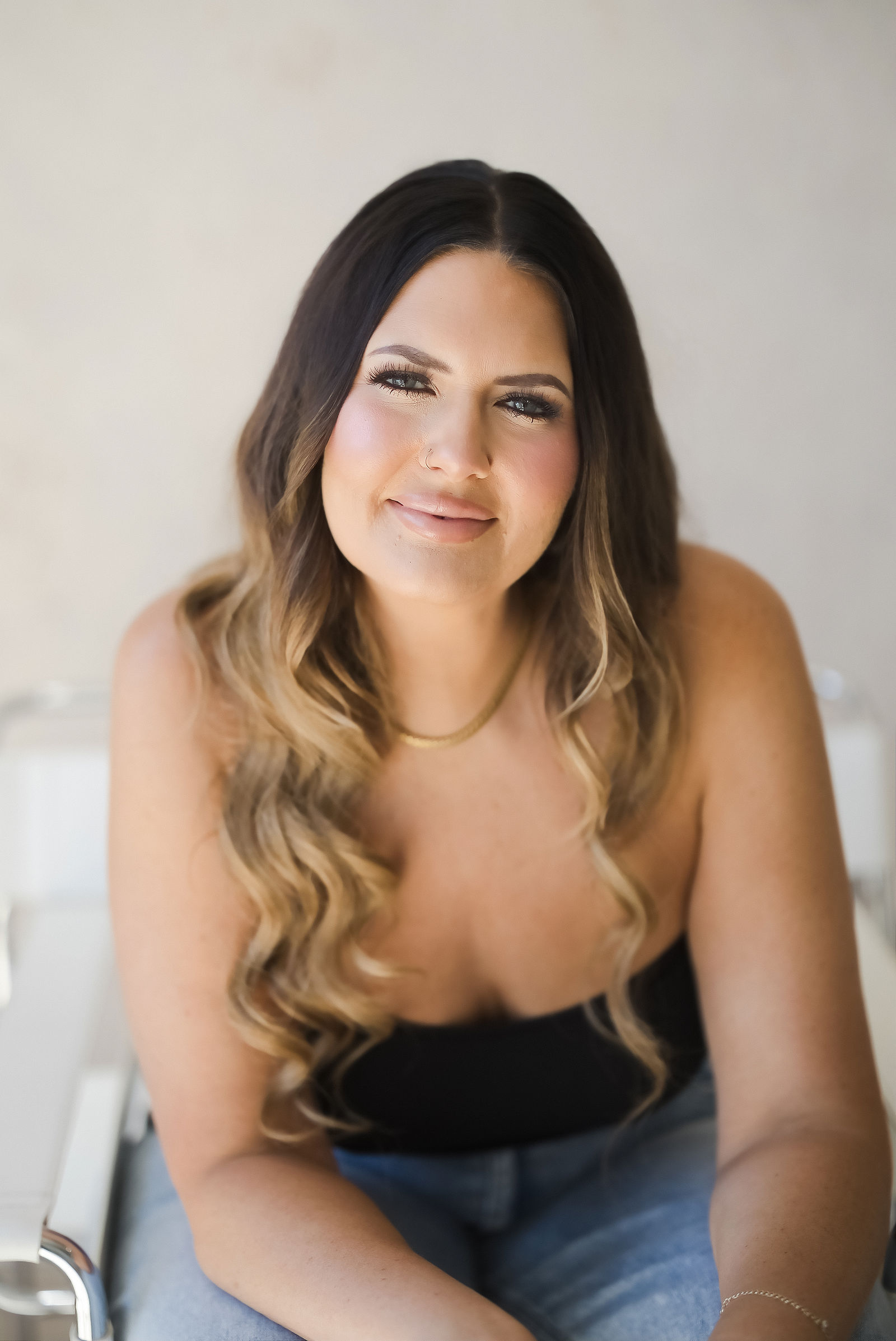 Personal brand photography of a beauty founder seated on a curved white sofa at The Studio on Fourth, Santa Rosa