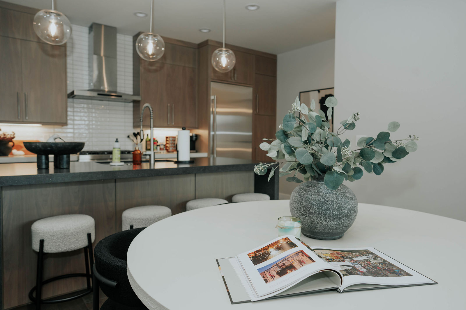 Light wood kitchen and round dining table with glass pendant lighting