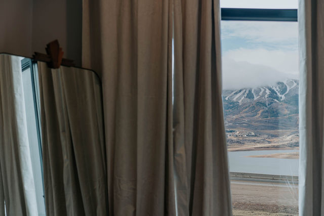 Soft curtains and a mirror framing mountain views