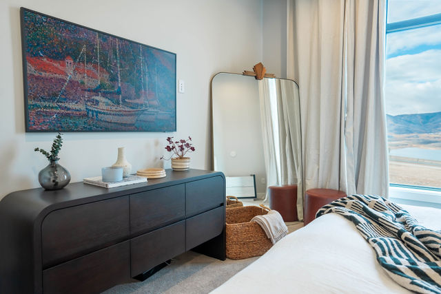 Dark bedroom dresser and artwork beside a full-height window