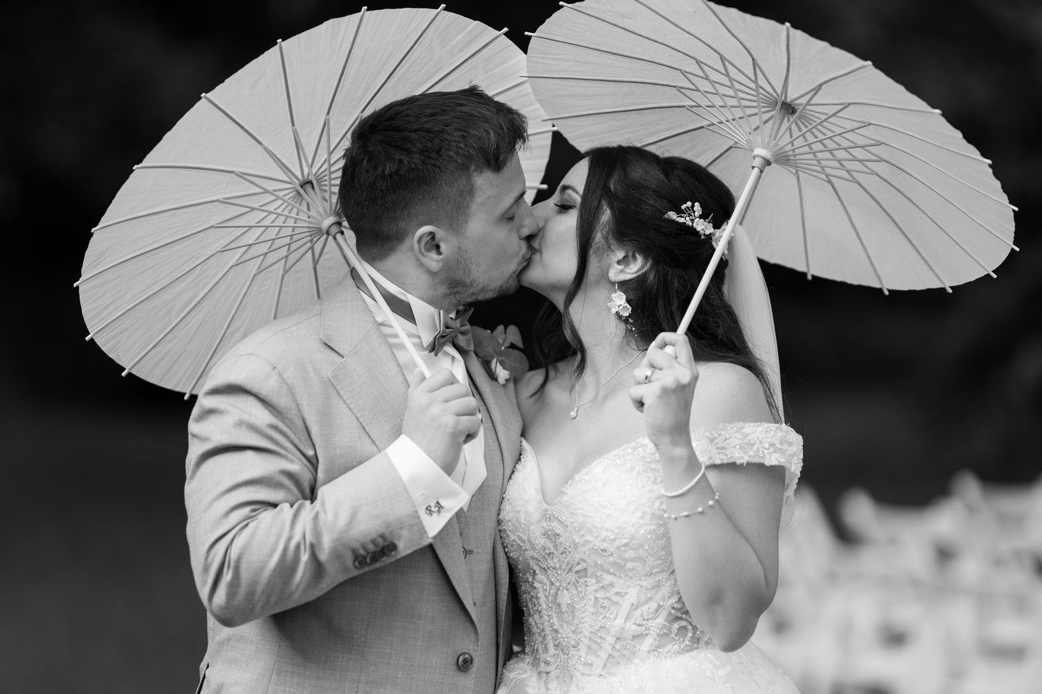 Adam und Roula küssen sich unter Papierschirmen, Schwarz-Weiß-Hochzeitsfoto von Hochzeitsfotograf Allan Feitor in Berlin