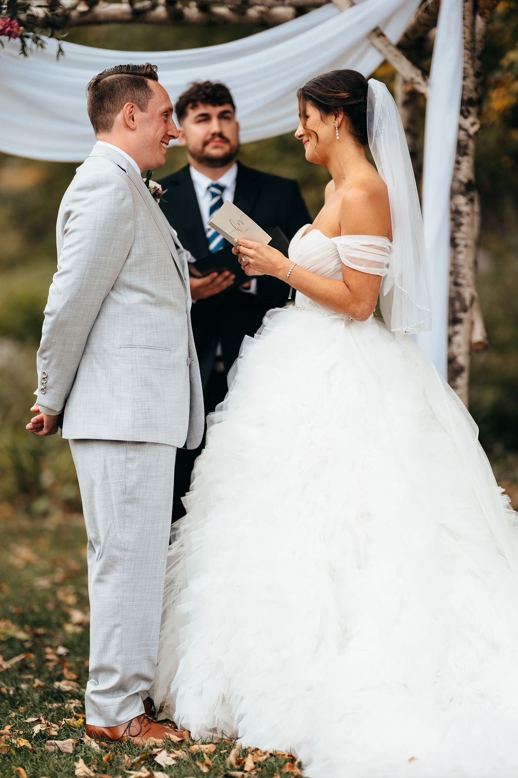 Heather and Brendan exchanging vows under a birch arch