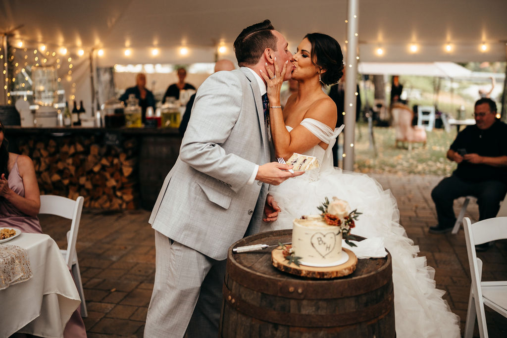 Heather and Brendan kissing while cutting their wedding cake