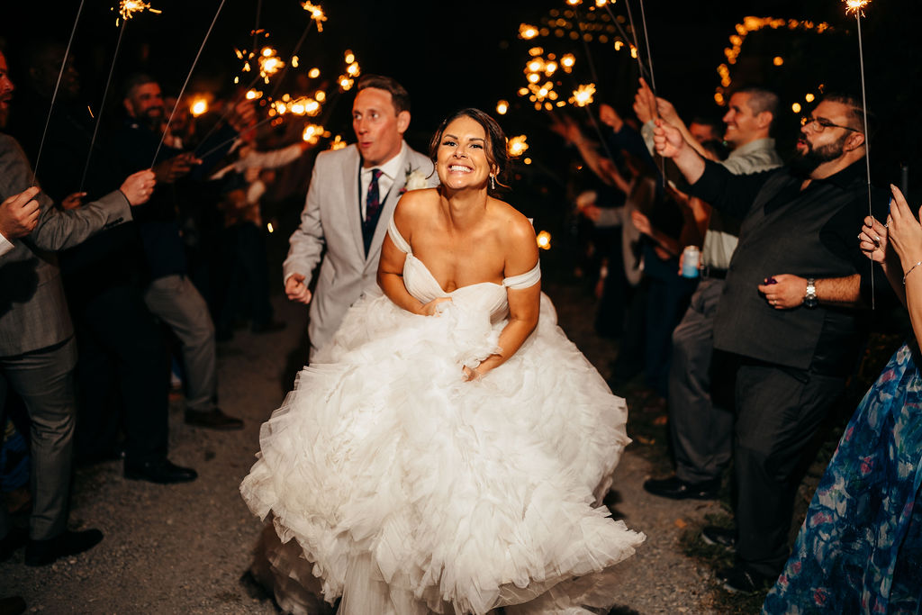 Heather and Brendan running through a sparkler exit at night
