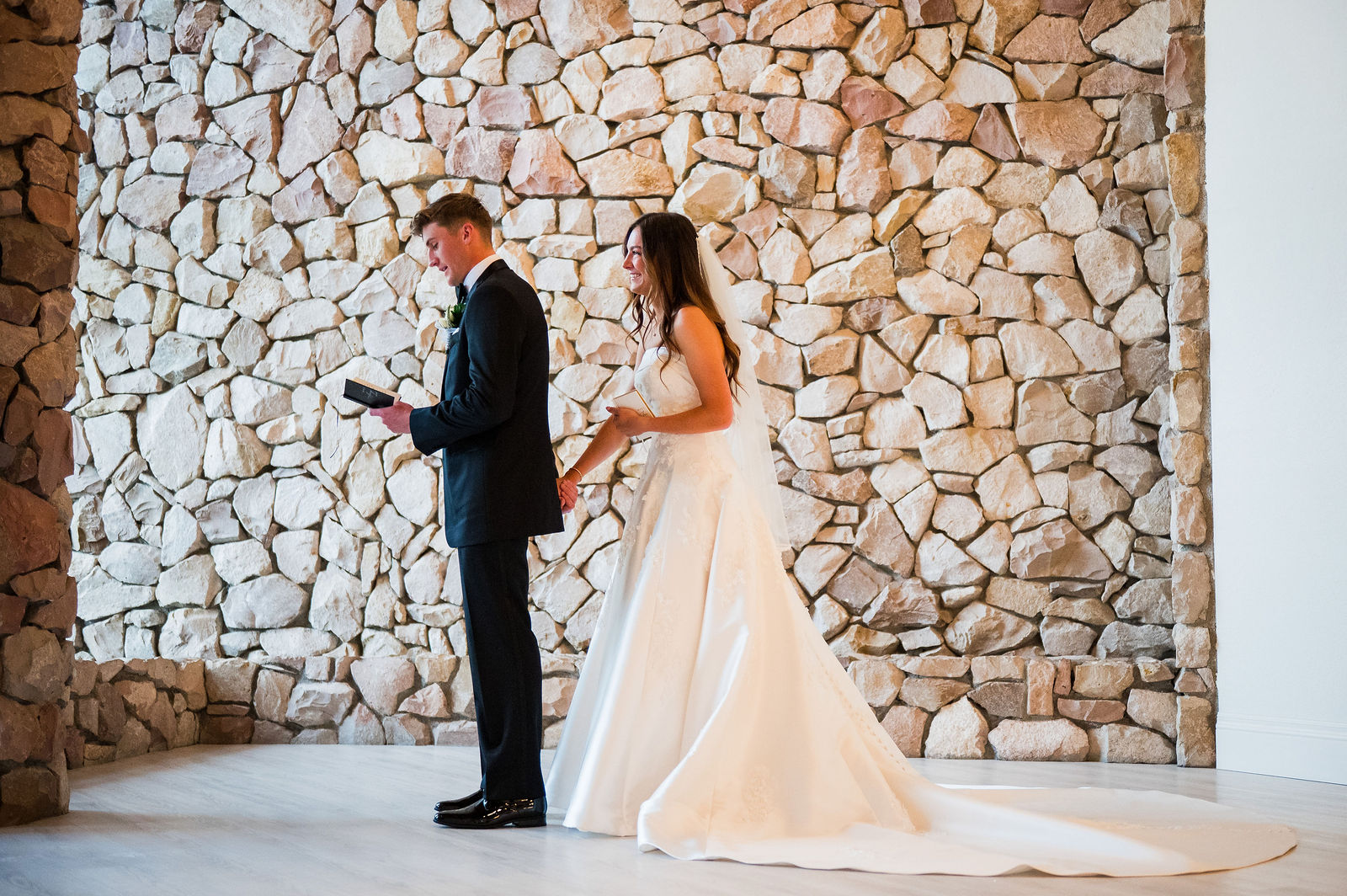 First touch and private vows against the stone wall at The Oaks at Plum Creek