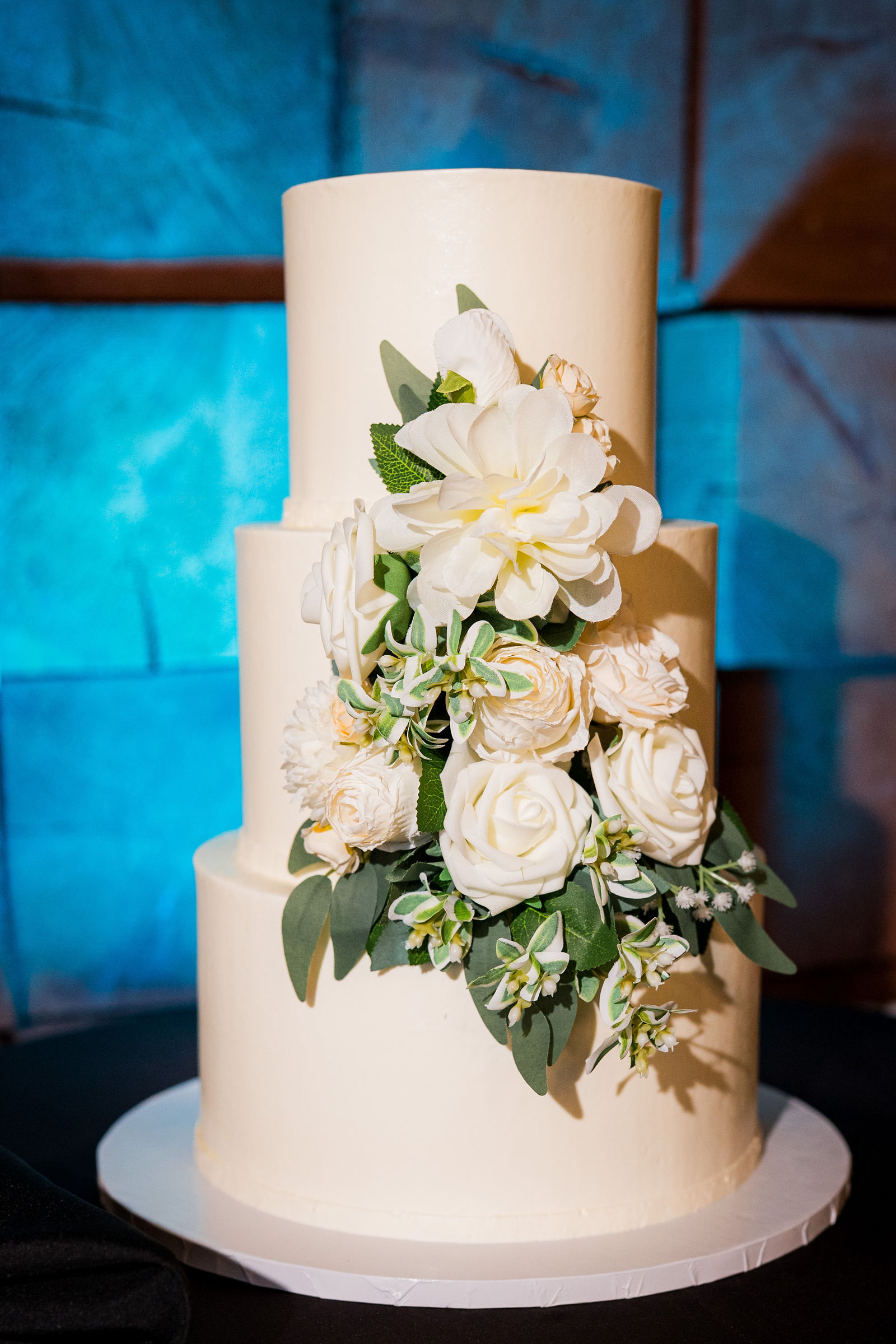 White tiered wedding cake with florals at The Oaks at Plum Creek Castle Rock