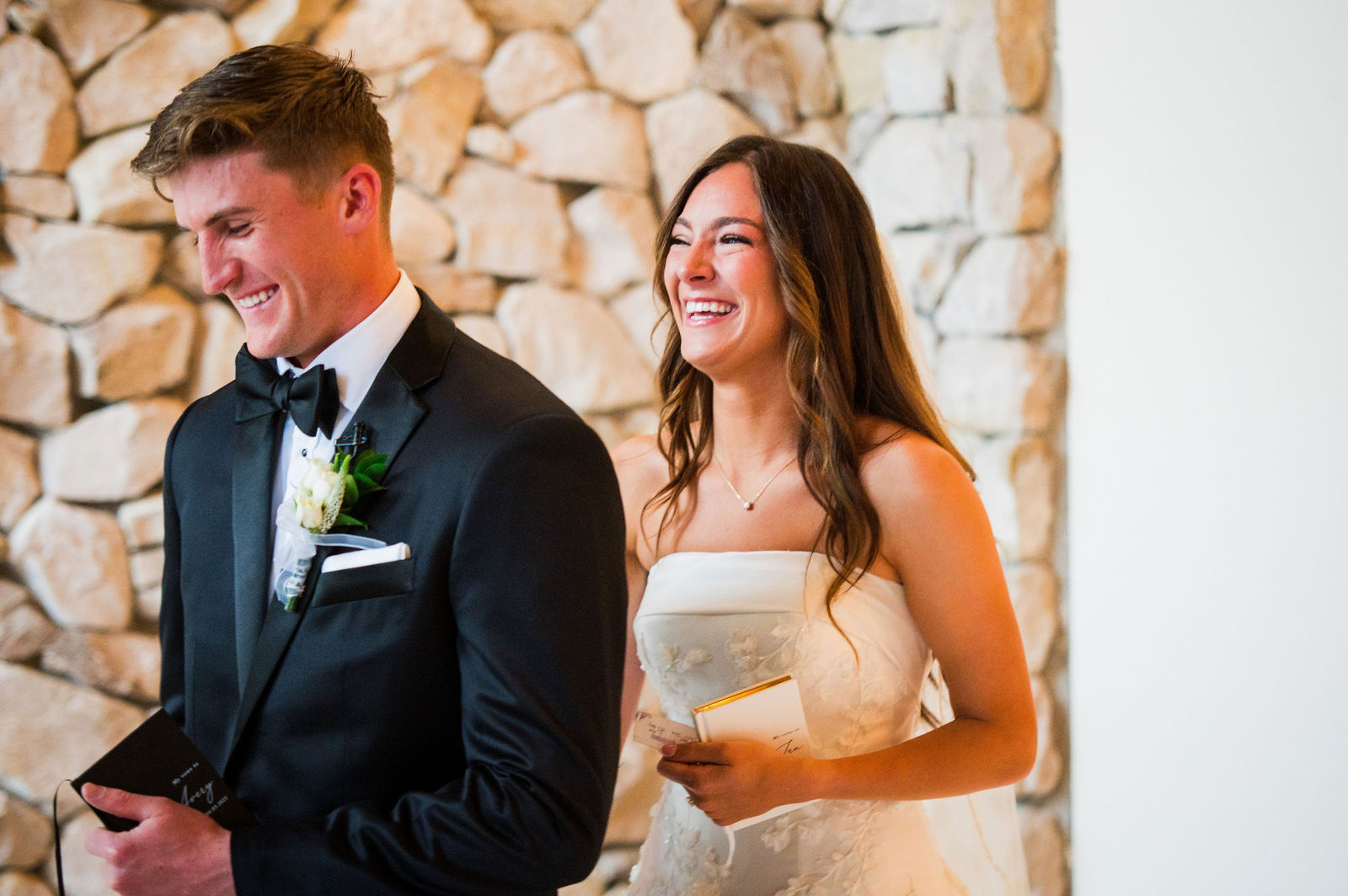Bride and groom laughing while reading private vows at The Oaks at Plum Creek