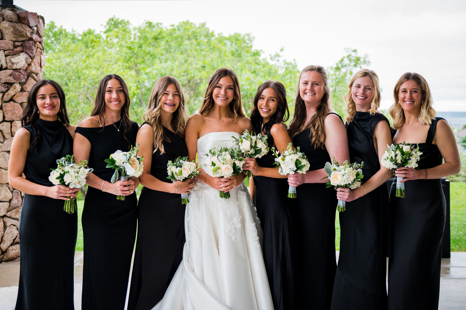 Bridesmaids in black gowns with the bride at The Oaks at Plum Creek Castle Rock