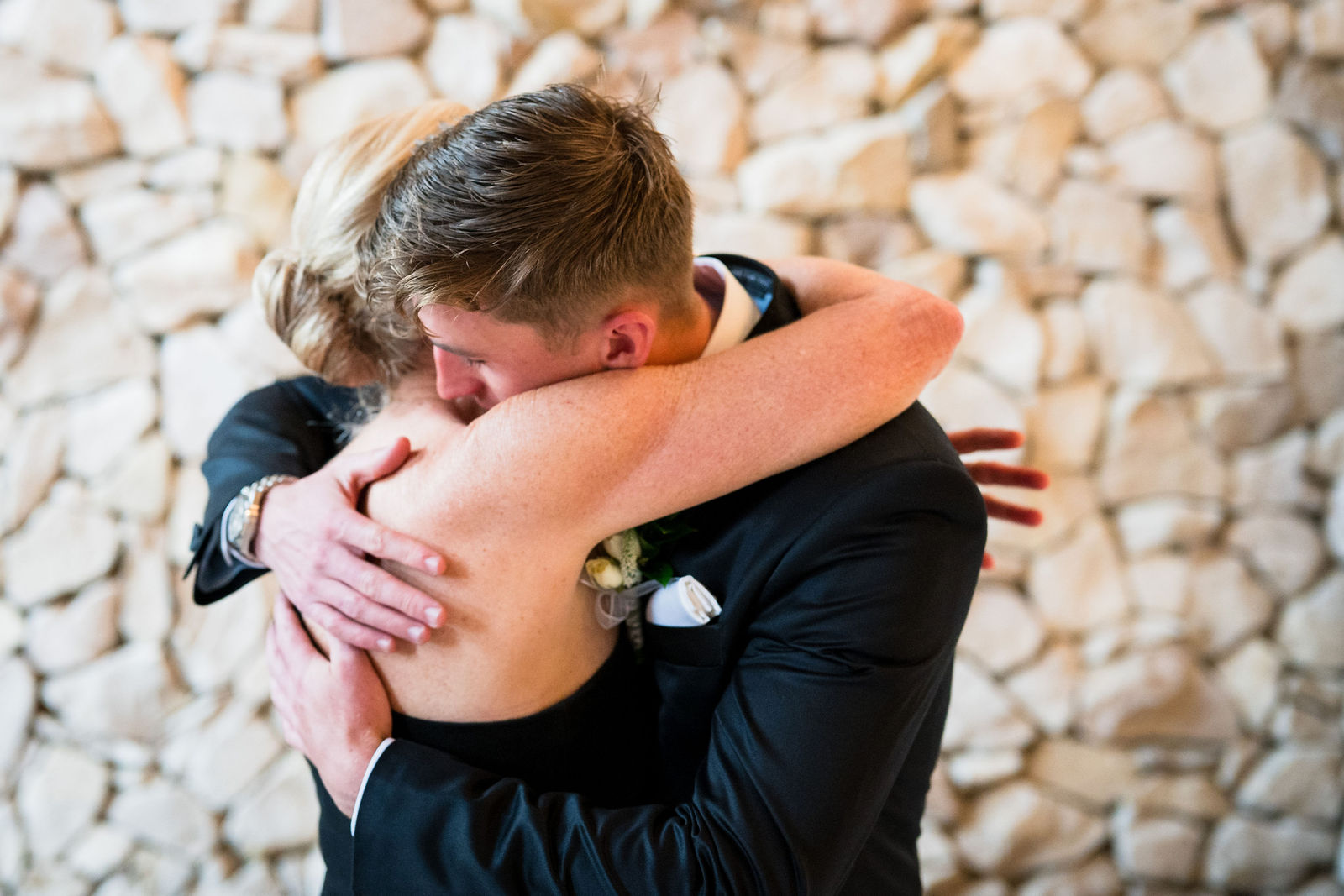 Groom hugging his father before a black tie wedding at The Oaks at Plum Creek