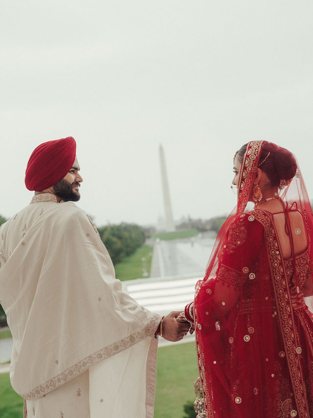 Avneet and Sarvan holding hands and looking at each other with the Washington Monument in the distance