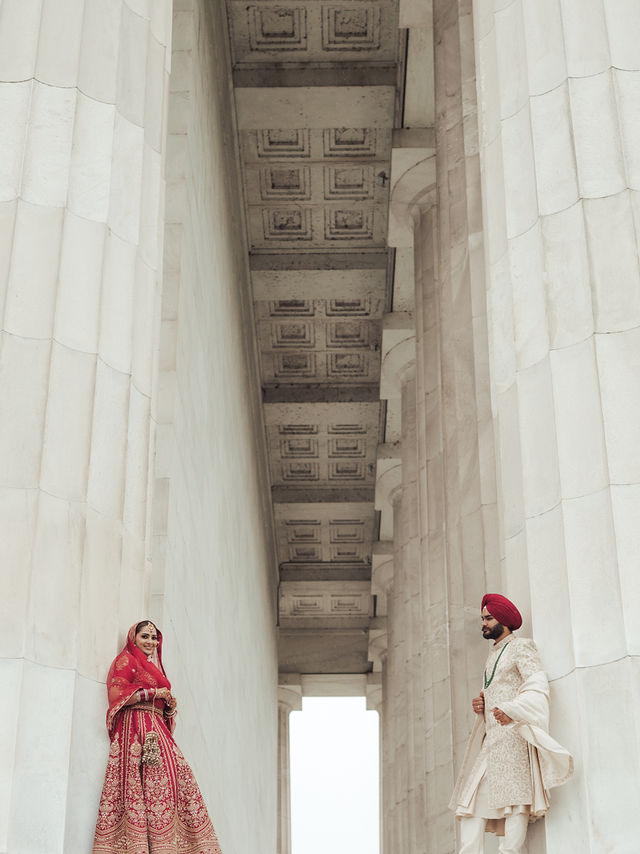 Avneet and Sarvan facing one another beneath a long stone colonnade