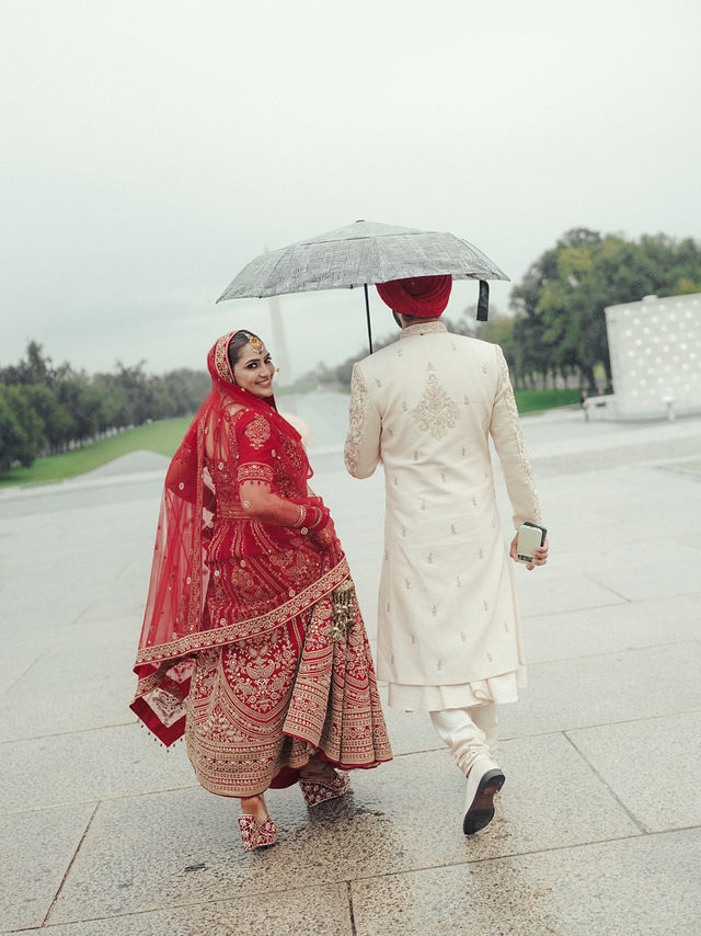 Avneet looking back as she and Sarvan walk together beneath an umbrella