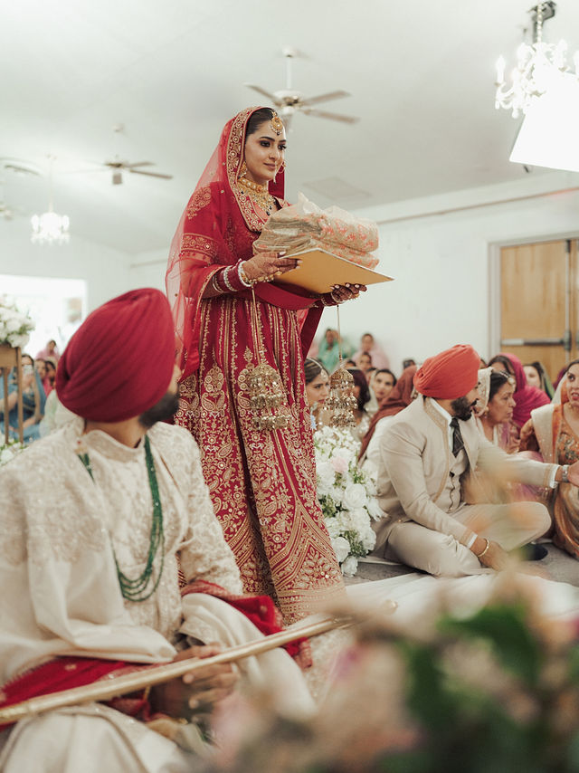 Avneet holding a ceremonial tray beside Sarvan, with guests seated behind them