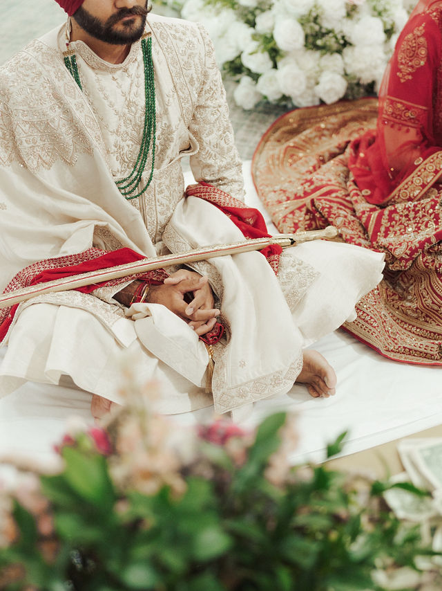 A close view of Avneet and Sarvan seated together during the ceremony beside white flowers