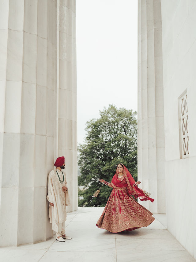 Avneet twirling in her red bridal outfit as Sarvan watches beside the stone columns
