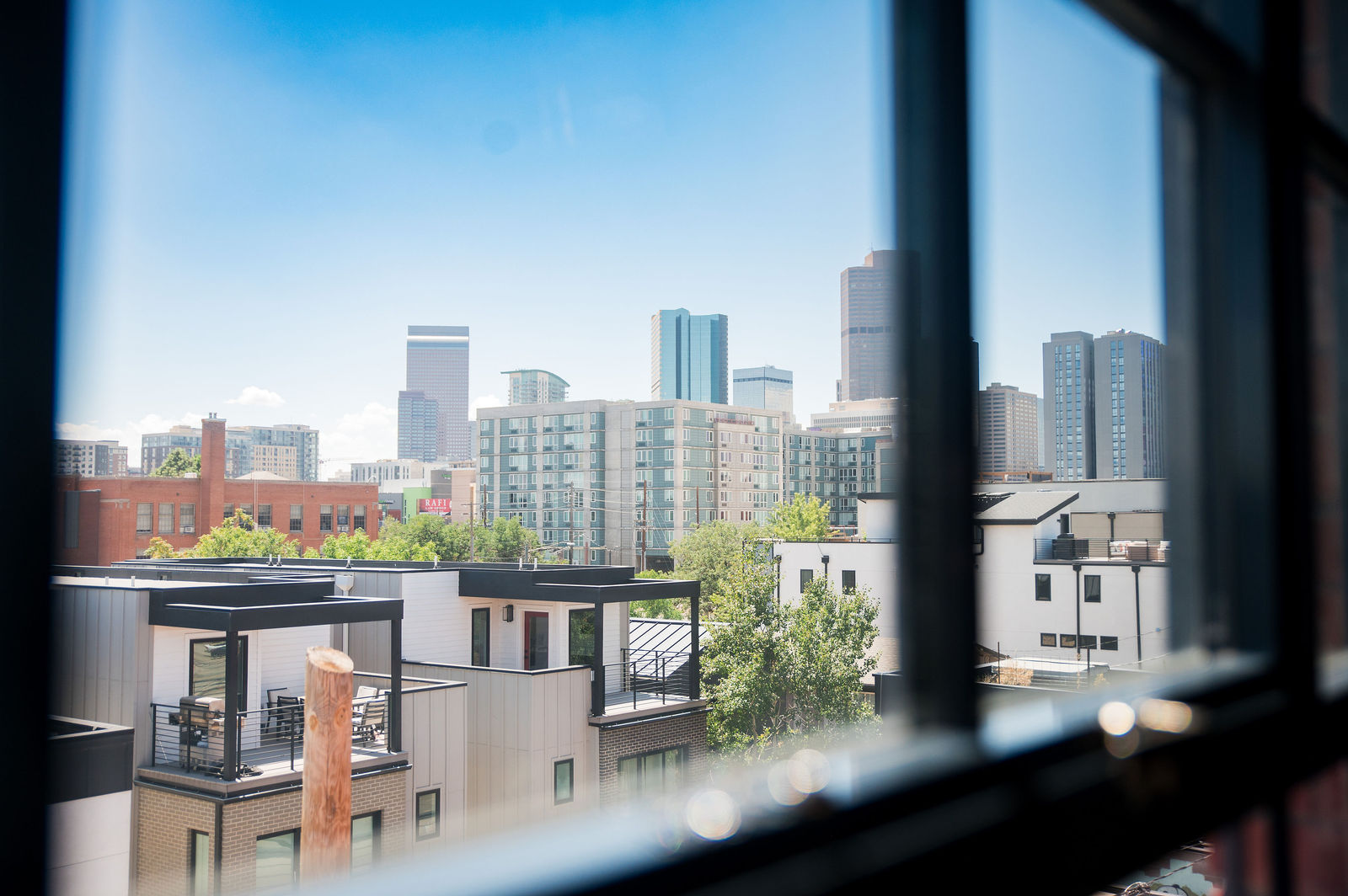 Wedding dress hanging in a window with the Denver skyline behind it