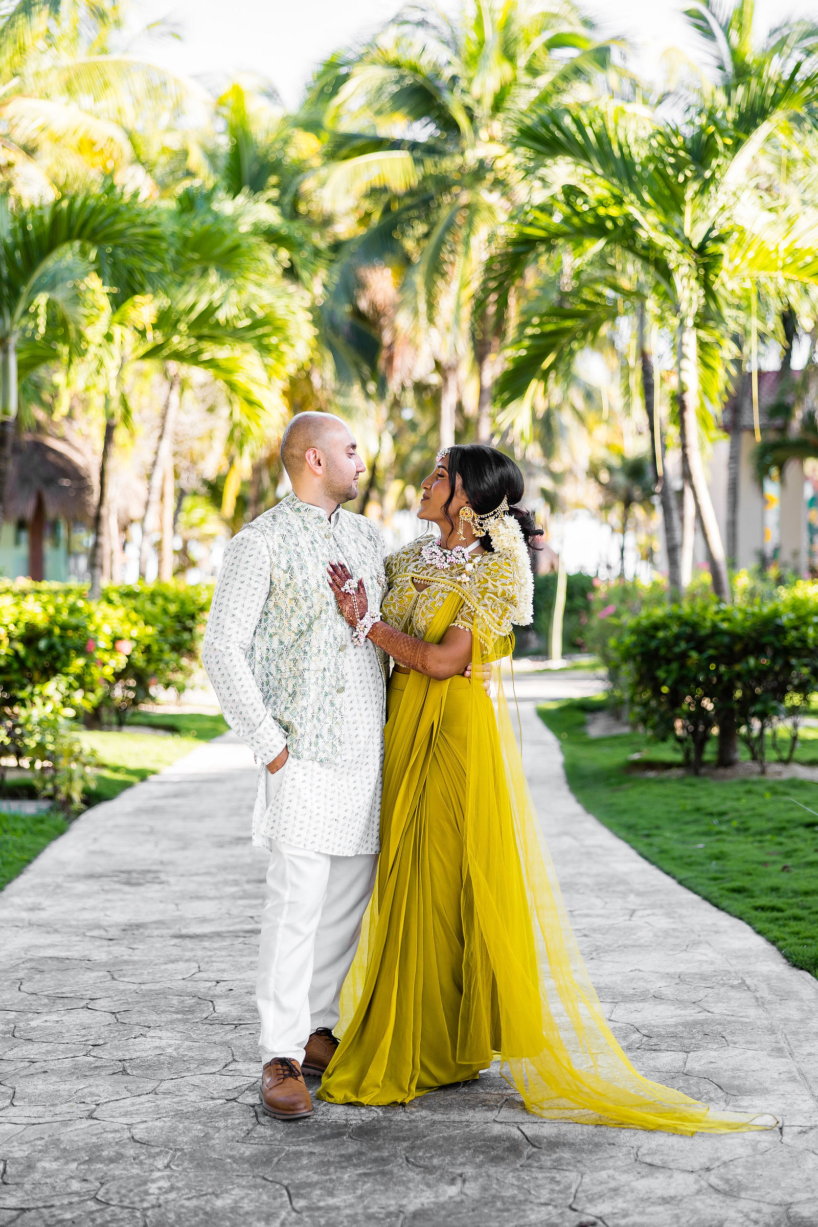 A couple in traditional dress on a garden path at their destination wedding
