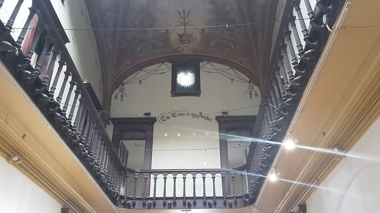 Historic balcony interior with wood railings and painted ceiling.