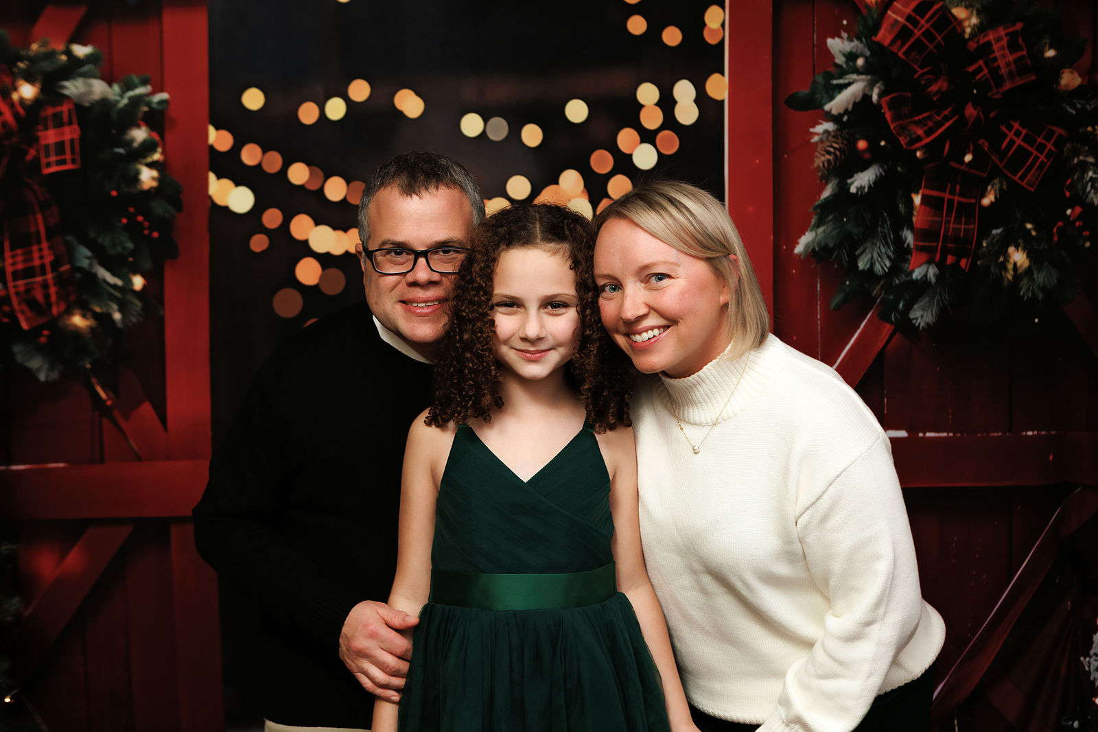 Young girl in an emerald green dress surrounded by warm Christmas lights