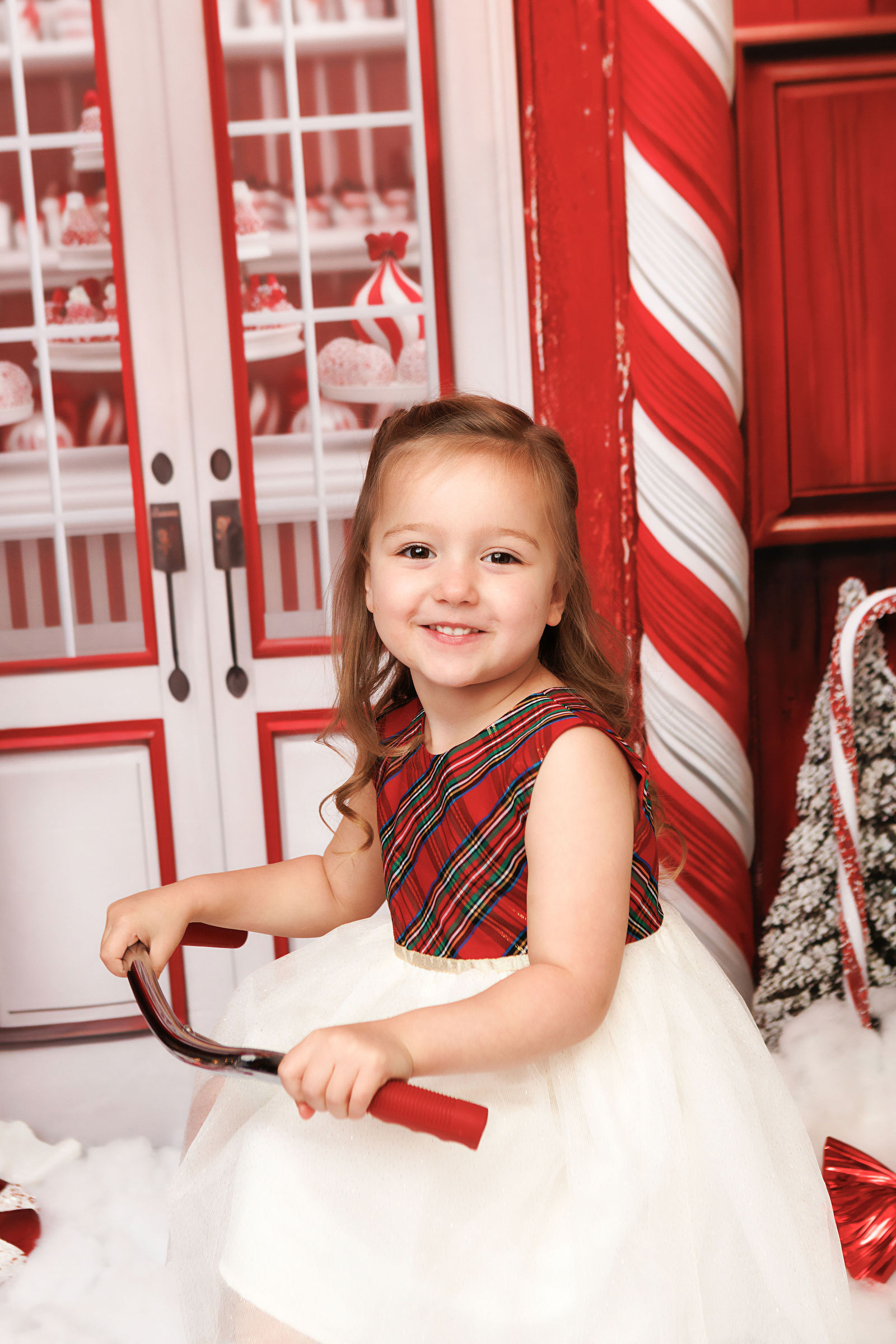 Young child on a vintage tricycle in a red and white Christmas set