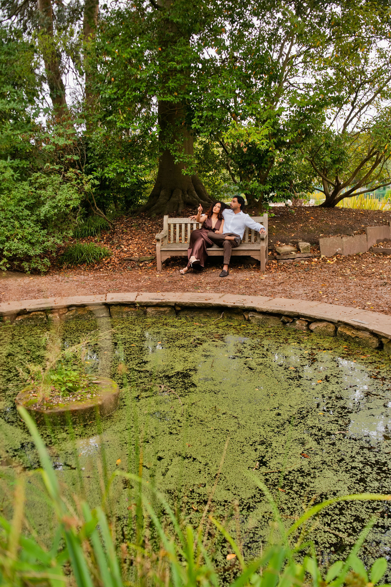 Suraj and Preshanti sharing a quiet moment beneath the trees beside the garden pond